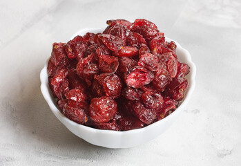 dried cranberries in a white bowl on a concrete background. Close-up. Selective focus.