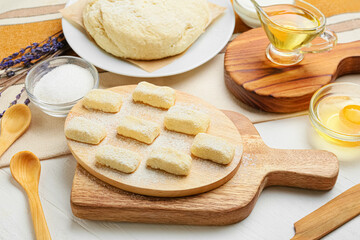 Board with raw lazy dumplings and ingredients on light wooden table