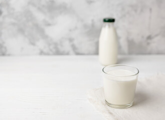 A glass of kefir and a bottle in the background on a concrete table with a place to copy. Selective focus.