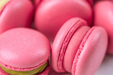 Macarons closeup on white wooden background. Sweet and colourful pink french macaroons. Cooking at home.