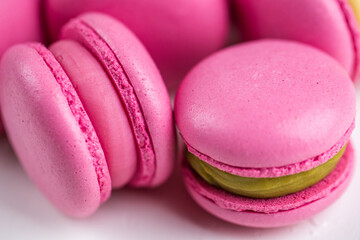 Macarons closeup on white wooden background. Sweet and colourful pink french macaroons. Cooking at home.