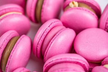 Fototapeta na wymiar Macarons closeup on white wooden background. Sweet and colourful pink french macaroons. Cooking at home.