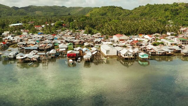 Fishing village with wooden houses standing on stilts in the sea from above. Dapa, Siargao, Philippines.