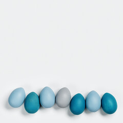 Painted Easter eggs blue, gray colored in row on white background with copy space. Chicken egg natural pastel shades. Easter holiday food, minimal design aesthetic flat lay