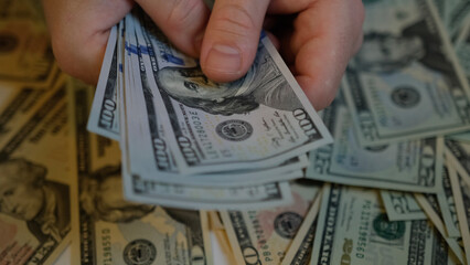 Male hands counting American one hundred dollar bills