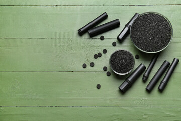 Composition with bowls of activated carbon powder, pills and bamboo sticks on color wooden...