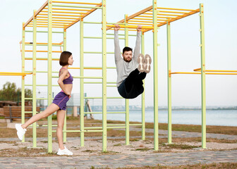 Sporty young couple training on bars outdoors