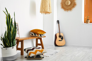 Interior of light room with wooden bench and guitar