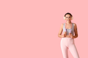 Sporty young woman with skipping rope and headphones on color background