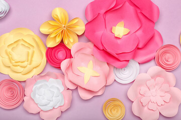 Beautiful handmade paper flowers on purple background, closeup
