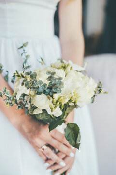 Close-up of a delicate beautiful wedding yellow light bouquet in the hands of the bride in a white dress. Wedding floristics and wedding preparations. Wedding background. Tenderness. 