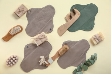 Hair brushes, soaps and reusable menstrual pads on yellow background