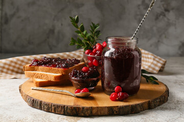 Jar of tasty lingonberry jam and toasts on grunge background