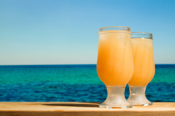 Two drinking glasses of orange cocktails.