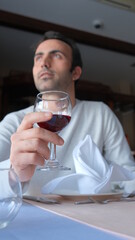 Man drinks wine in minimal luxury restaurant in hotel for summer time. 