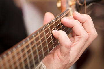 Guitar Player Hand or Musician's Hand in F Major Chord on Acoustic Guitar String in Soft Natural Light in Side View