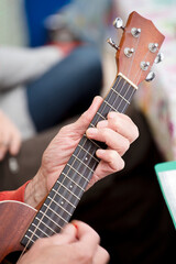 Fototapeta na wymiar Guitar Player Hand or Musician's Hand in F Major Chord on Acoustic Guitar String in Soft Natural Light in Side View