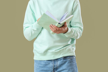 Young man with book on green background