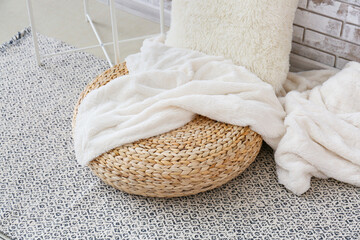 Modern wicker pouf with plaid in room, closeup
