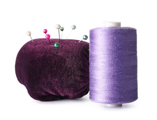 Violet sewing thread spool and pincushion with pins on white background