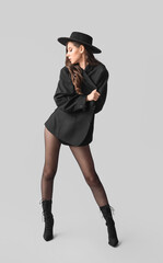 Fashionable young woman in black tights on grey background