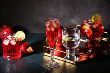 Glasses of tasty pomegranate cocktail on black background