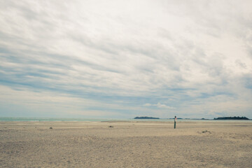 Distant land on horizon seen from sandy beach with dramatic clouds in sky. Coastal Georgia. Tybee Island.