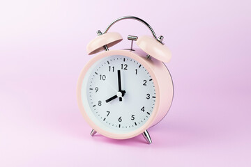Classic Pink alarm clock on pink pastel background.