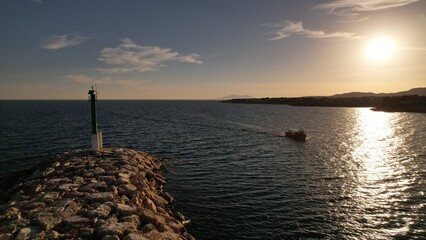 barca de pesca entrando a puerto en un atardecer