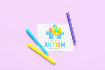 Paper sheet with text WORLD AUTISM AWARENESS DAY and felt-tip pens on lilac background