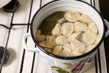 Homemade dumplings are cooked in a pan on a gas stove. Ukrainian traditional food, top view, copy space.