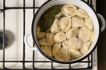 Homemade dumplings are cooked in a pan on a gas stove. Ukrainian traditional food, top view, copy space.
