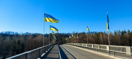 Ukraine flag. Ukrainian blue and yellow flag. Background of blue sky and white clouds. The national flag of Ukraine. National flags of Ukraine and bridge Latvia
