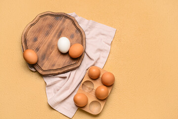 Holder and wooden board with fresh chicken eggs on beige background