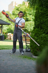 Full length portrait of caucasian man wearing overalls, safety glasses, headphones and gloves using...