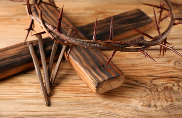 Crown of thorns with wooden cross and nails on wooden background