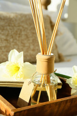 Box with reed diffuser, notebook and flowers on bed, closeup