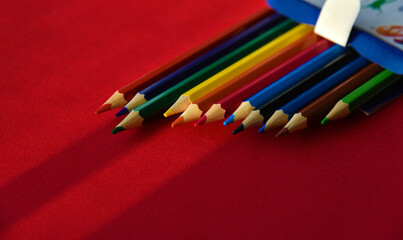 Multicolored pencils on a red background in the light