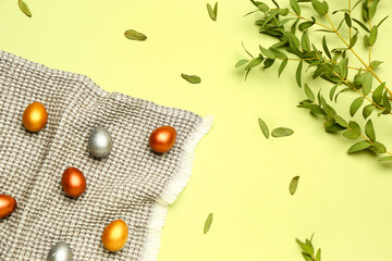 Painted Easter eggs and eucalyptus leaves on green background