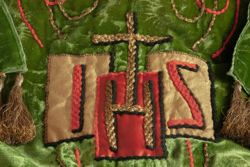 Priestly vestment up close. Symbol of Jesus Christ in letters and with gold cross. Latin or Greek...