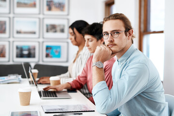 So many plans to try out. Cropped portrait of a handsome young businessman sitting and looking contemplative while his colleagues work behind him in the office.
