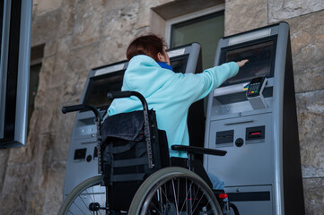 A Caucasian woman in a wheelchair does not reach the self-service checkout at the railway station. Hard-to-reach environment.