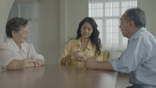 Holiday concept of 4k Resolution. Asian families take turns discarding cards on the table while playing games at home. Family gambling games.