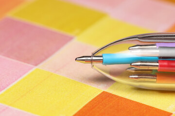 Multi color ball point pen on checkered colorful background.