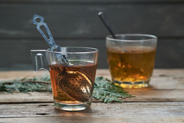 Two cups with red tea on rustic wooden table.