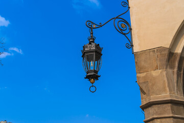 Antique street lighting lantern on the wall of the house against the blue sky