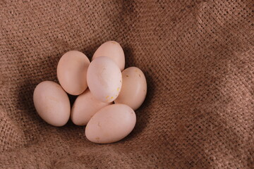 Fresh free-range chicken eggs with brown cloth nest, A pile of white eggs in the nest, selective focus