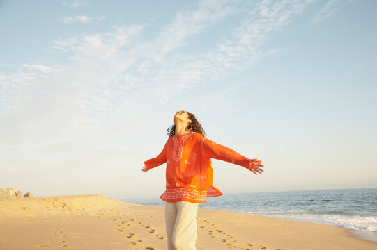 Joyful woman with arms extended on beach on vacation