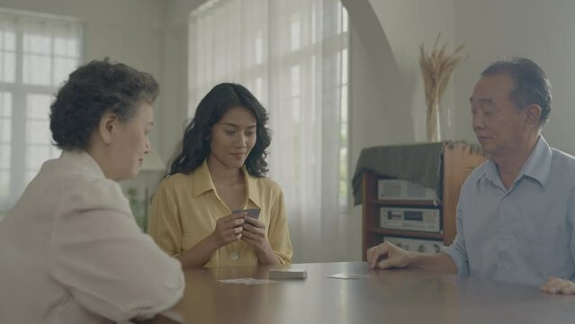 Holiday concept of 4k Resolution. Asian families take turns discarding cards on the table while playing games at home. Family gambling games.