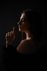 Sexy silhouette of a beautiful girl on a dark plain background. Portrait.